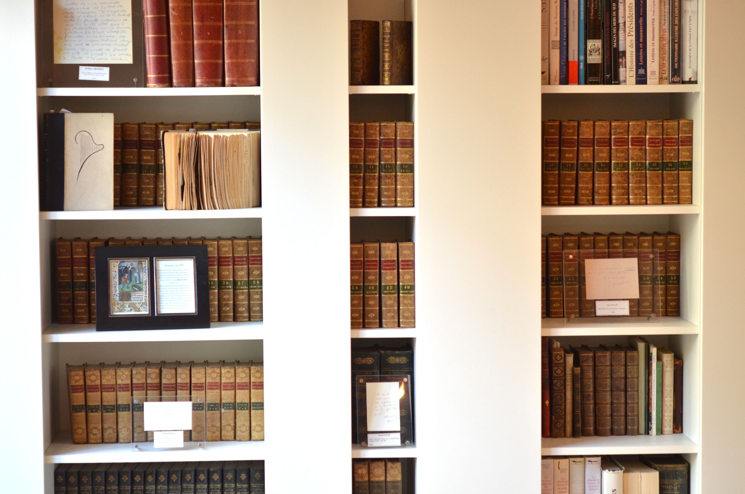 Bibliothèque, livres reliés et cadres Una biblioteca piena di libri rilegati e autografi incorniciati